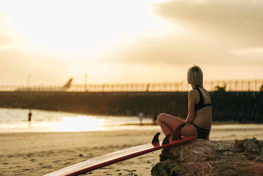 A surfing woman gazes into the ocean