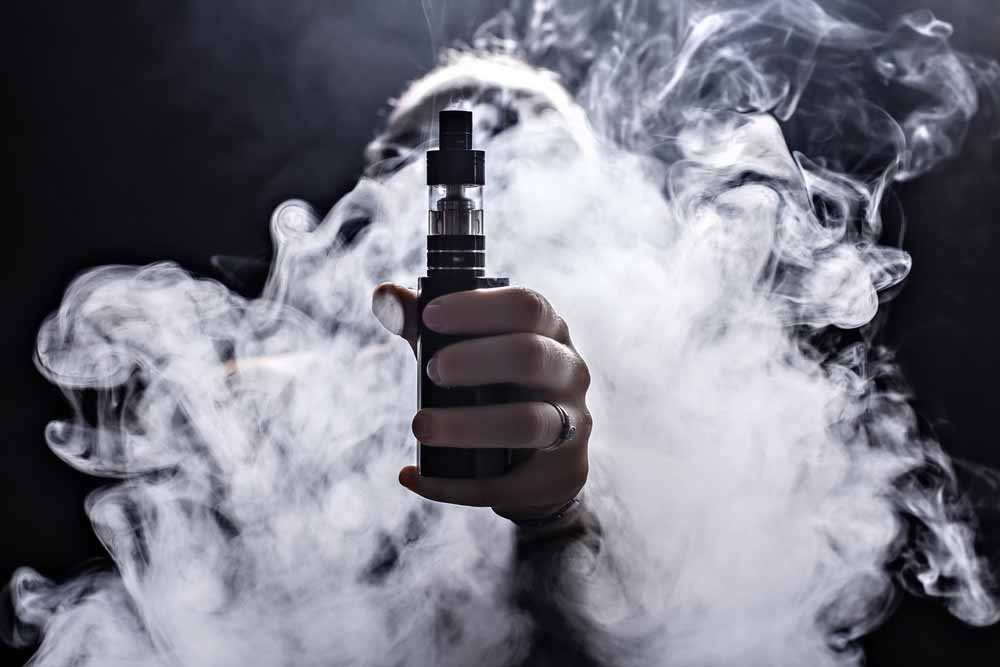 Image of a hand emerging from smoke with vape pen