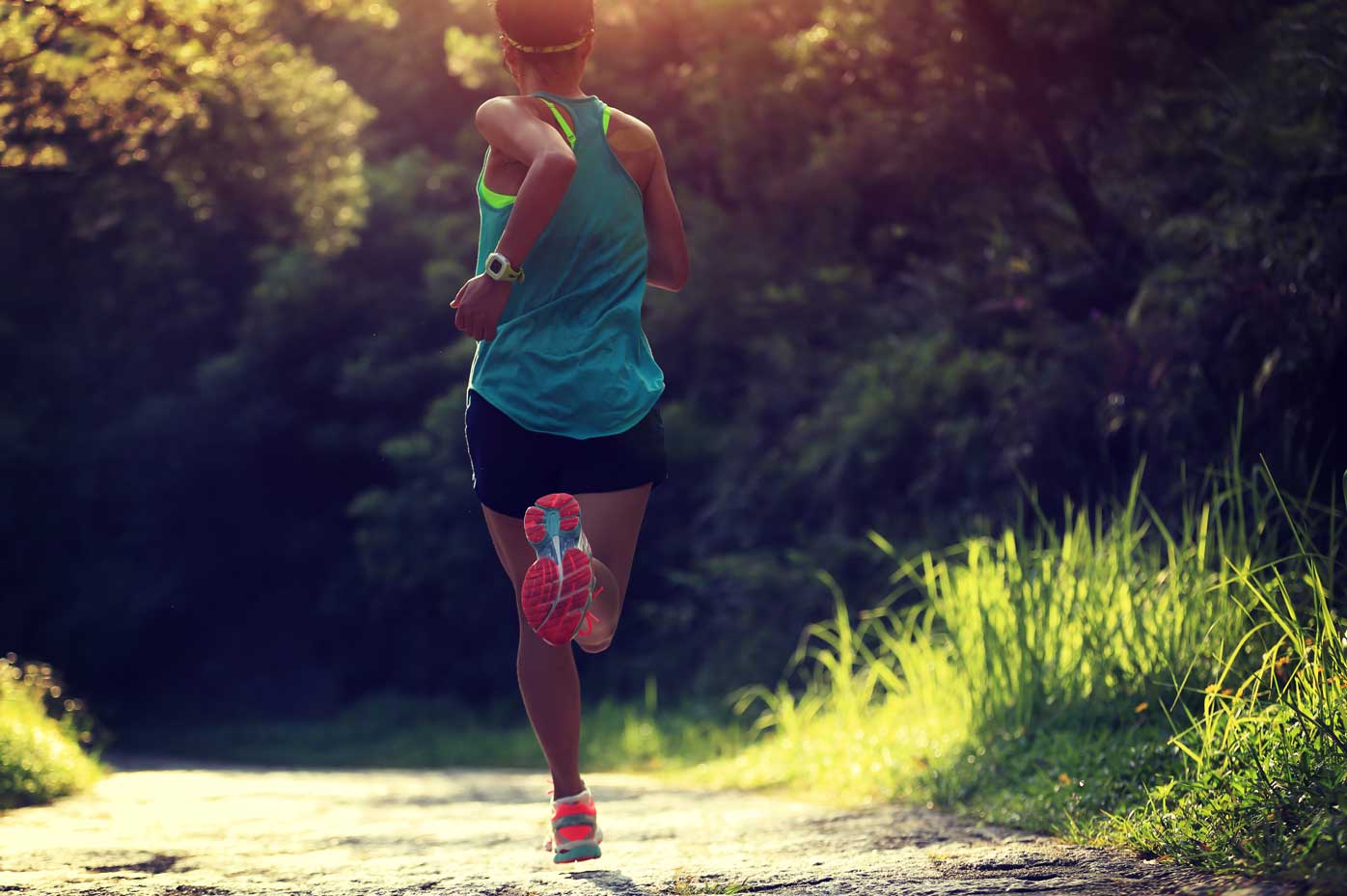 A female runner in profile exercises in a wooded park