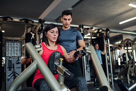 Woman lifting weights with trainer