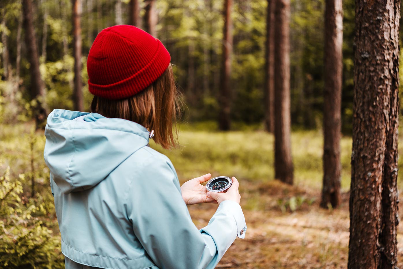 Woman standing in the woods looking at a compass