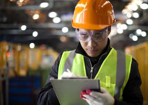 A worker wearing a hard hat and performing checkouts