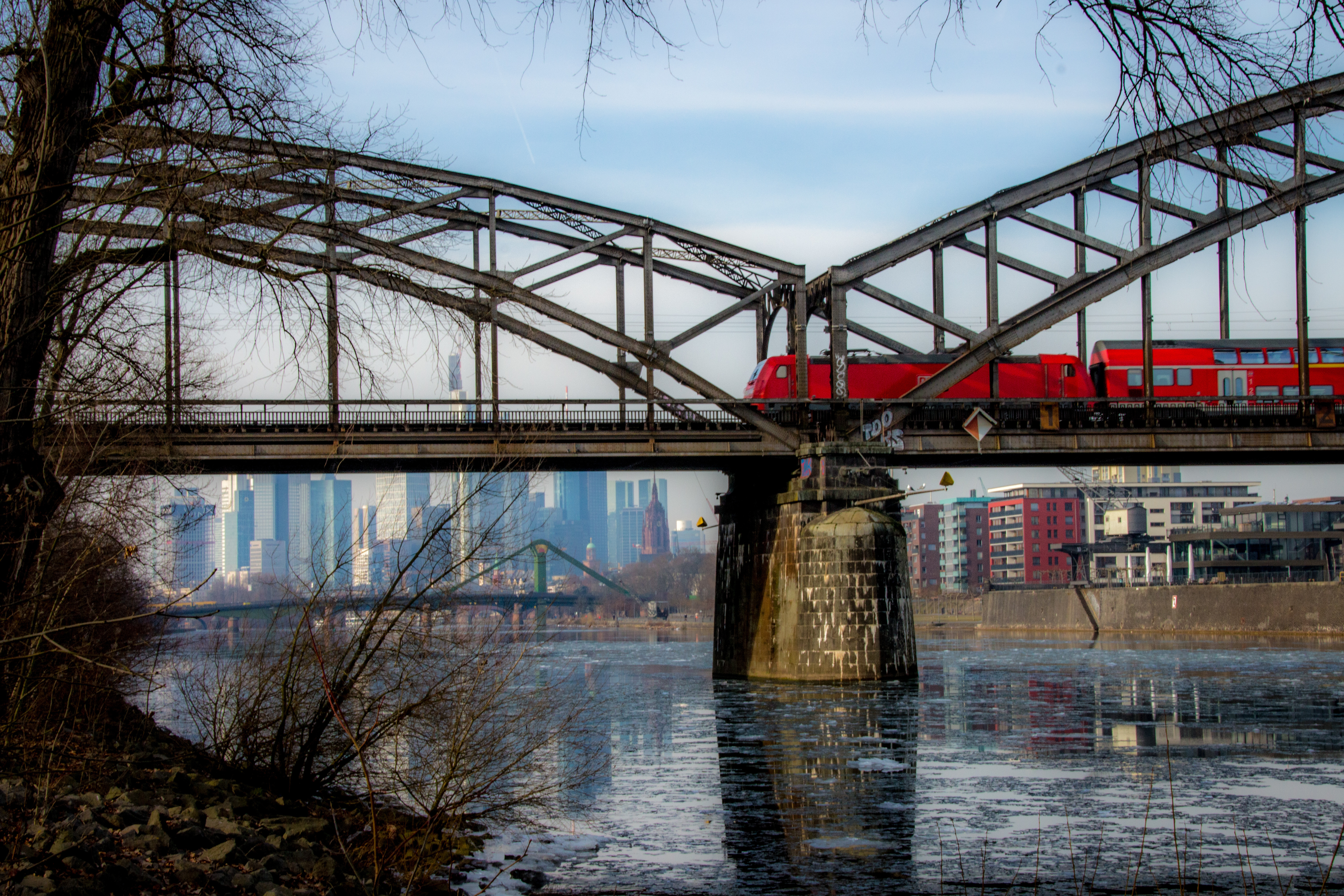 Train on a bridge in Frankfurt, Germany, with the city skyline in the background.