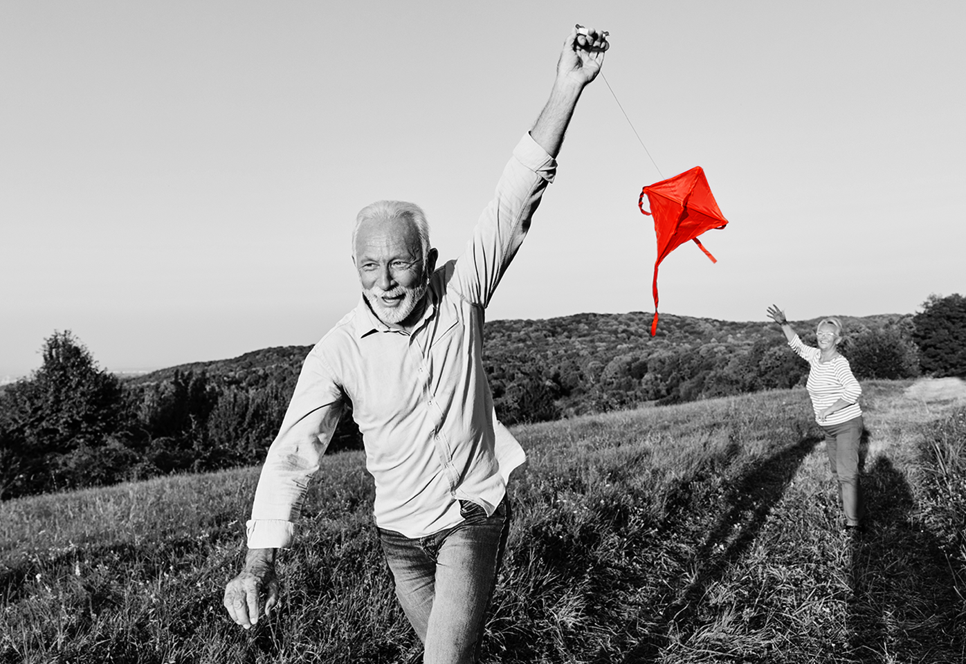 Older gentleman flying a kite with his wife.
