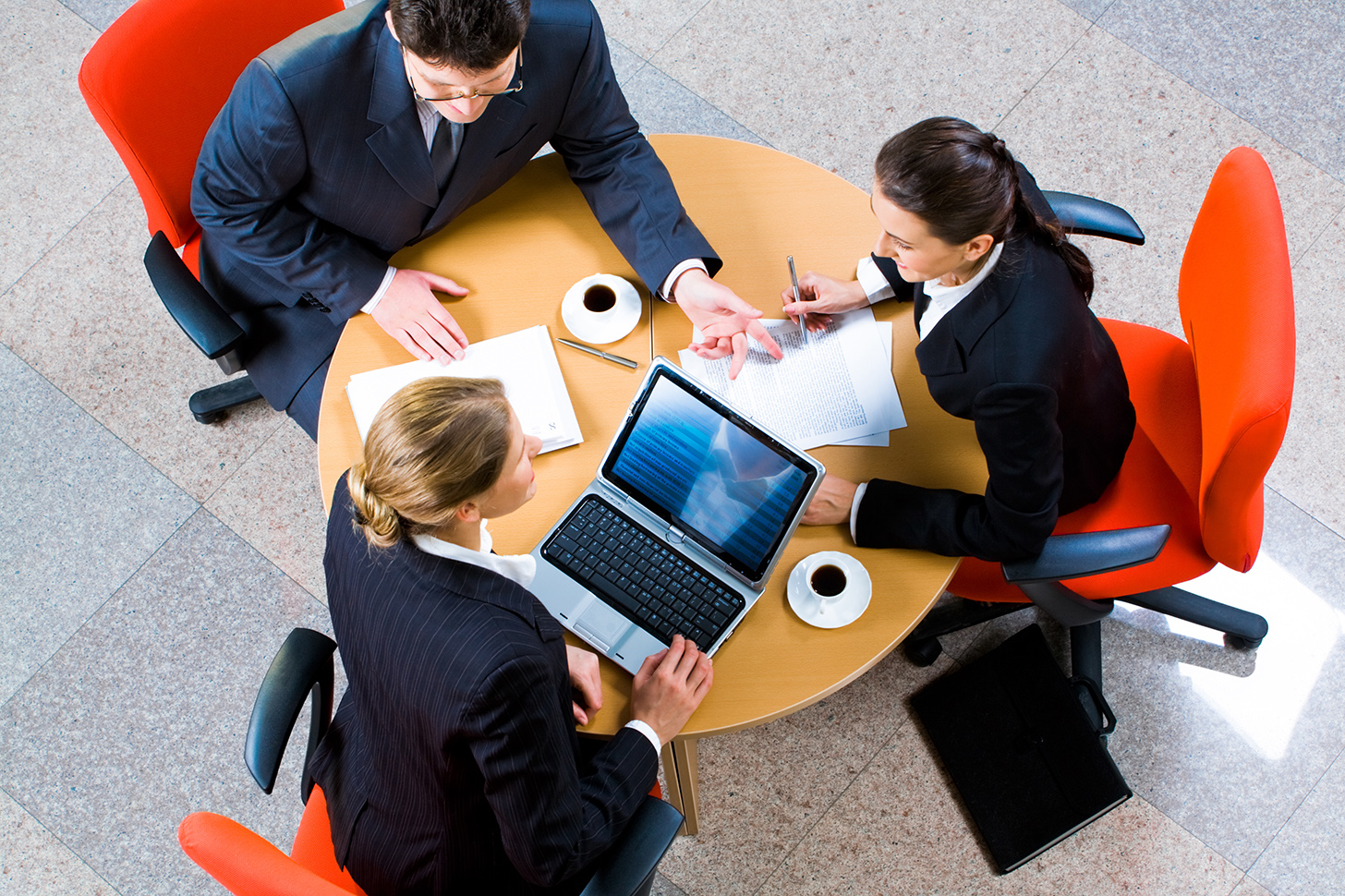 Three business people meeting around a round conference table.