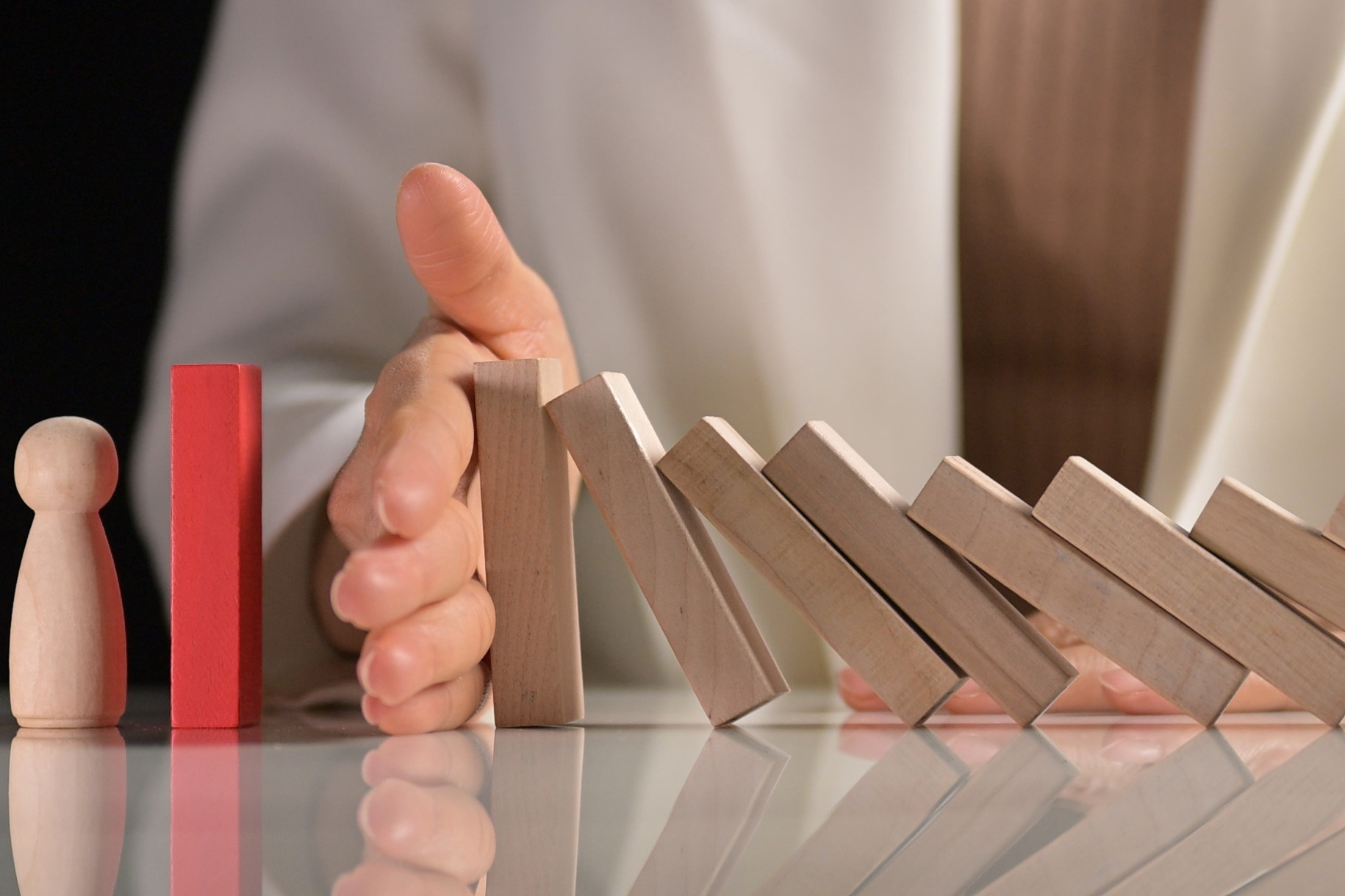 Hand stopping dominoes from falling.