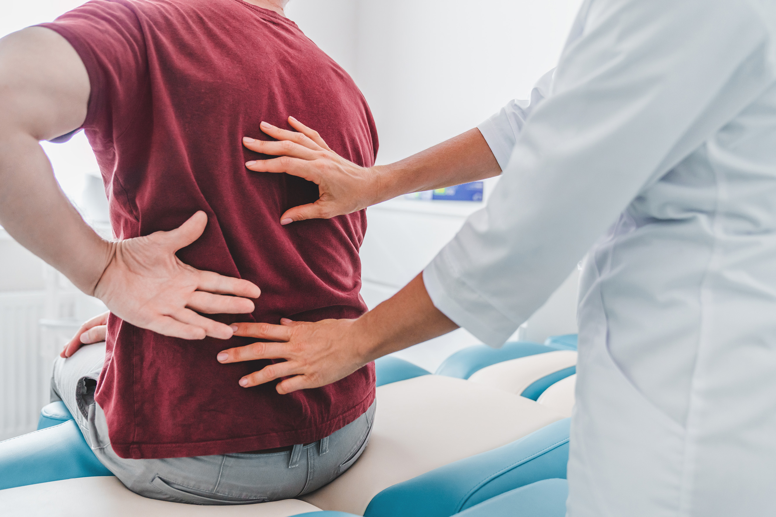 A man with back pain being examined by a doctor
