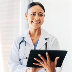 A female physician smiles while holding a tablet device