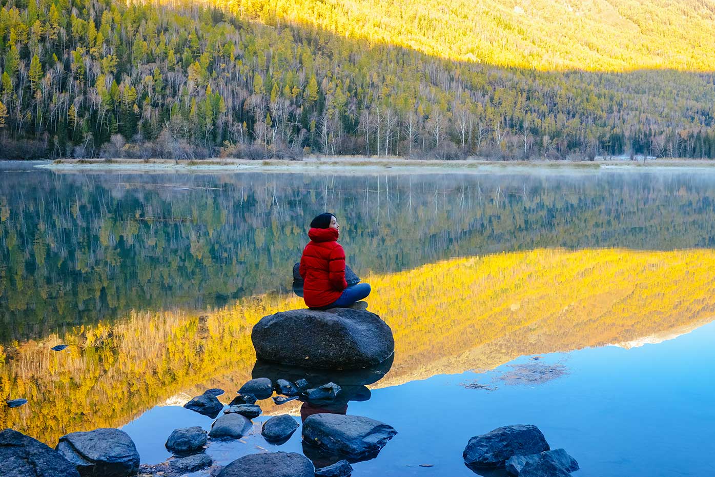 Woman sitting on rock at the lake