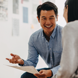 A man smiles while explaining a document