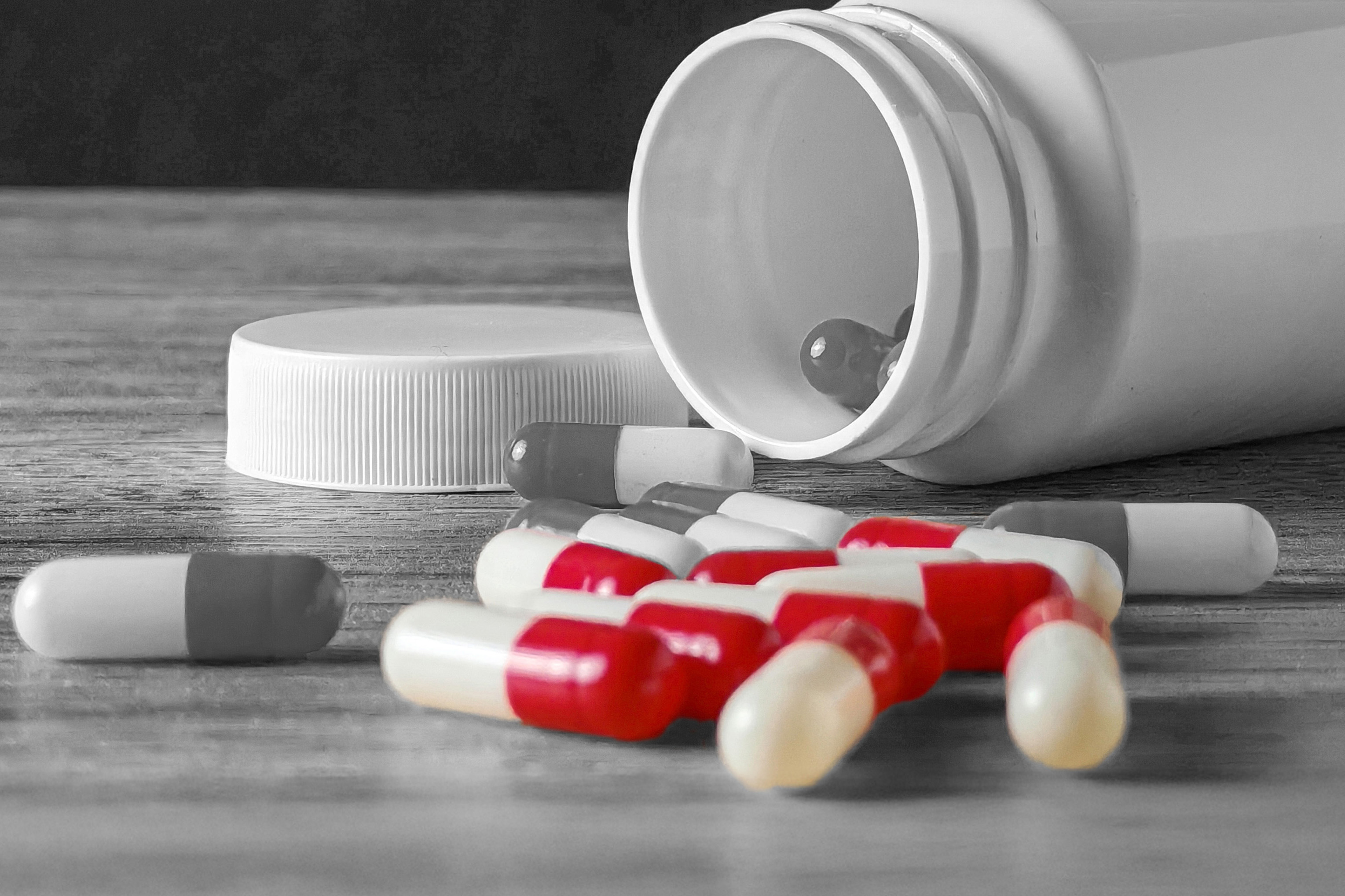 Open pill bottle with pills on table