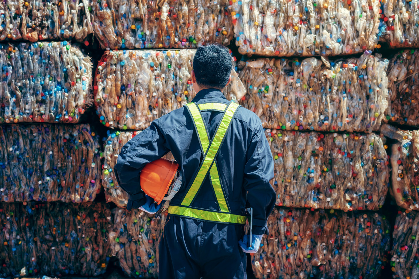 Engineer stands in front of bales of recycled plastic bottles