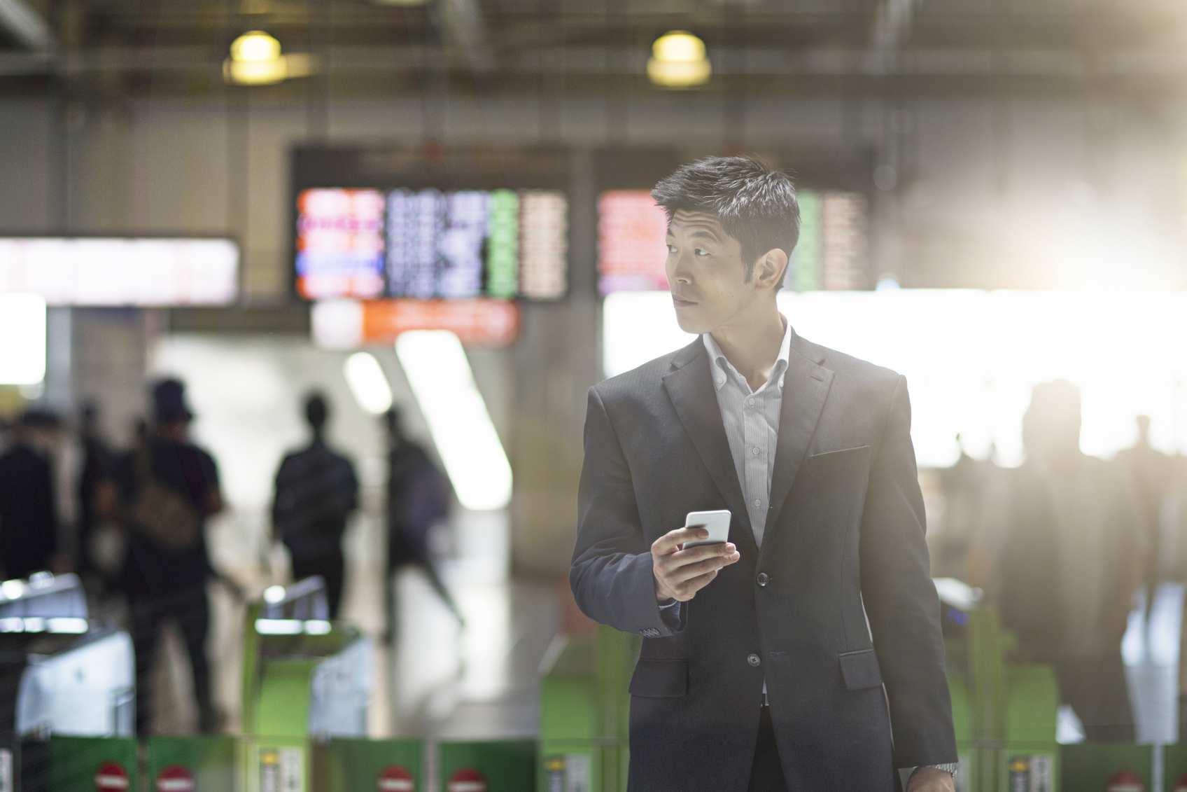 A policyholder in Asia clutches a smartphone and moves through an airport terminal