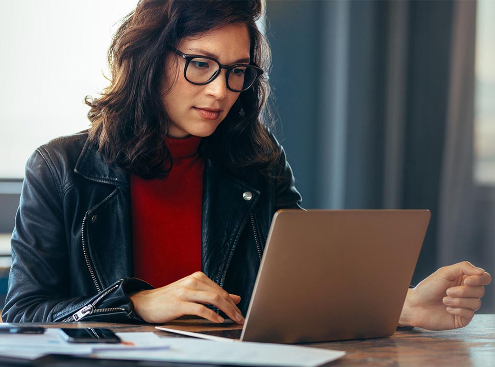A woman peers into a laptop, looking carefully on her laptop screen