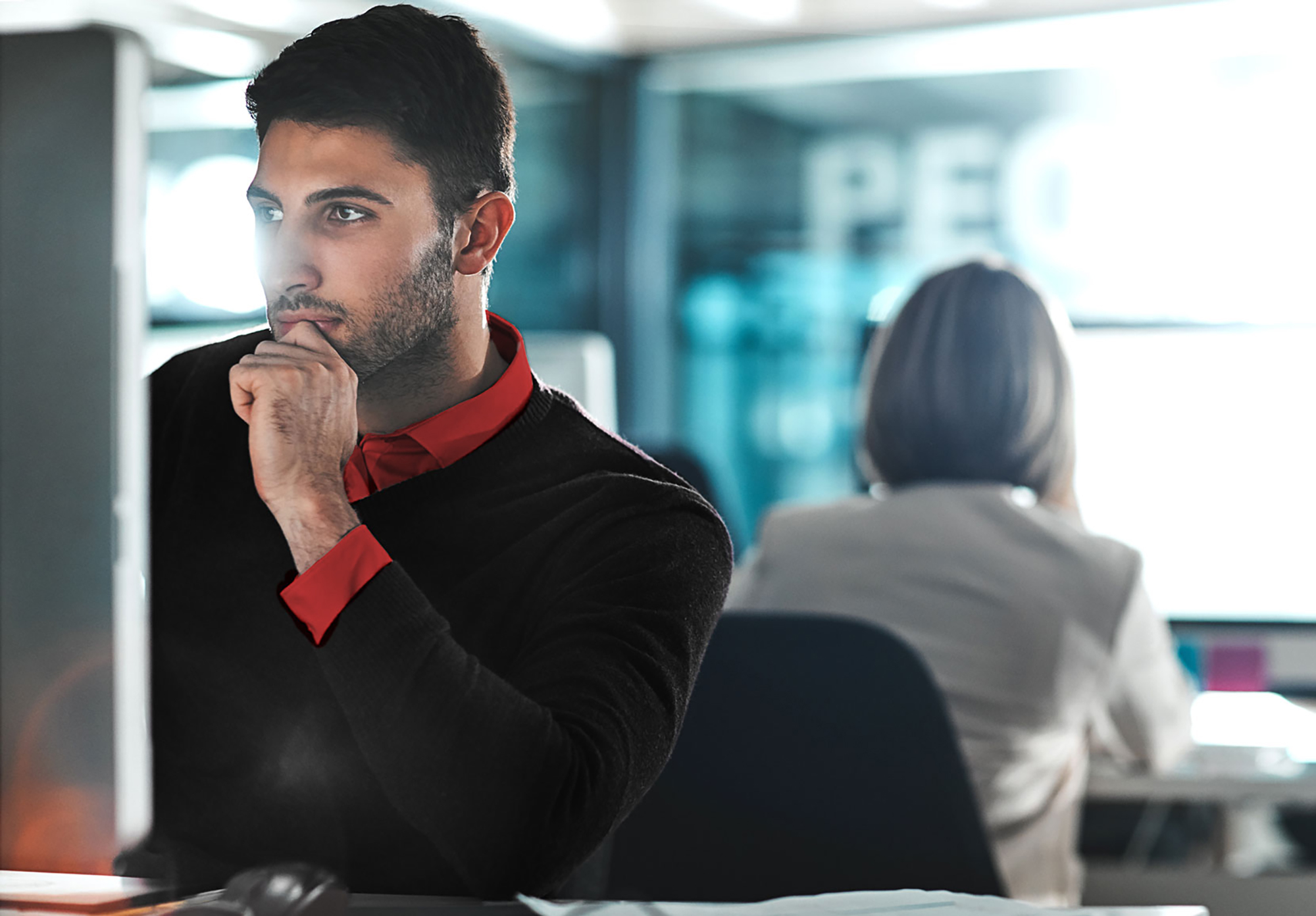 An underwriter gazes pensively at a case on his computer.