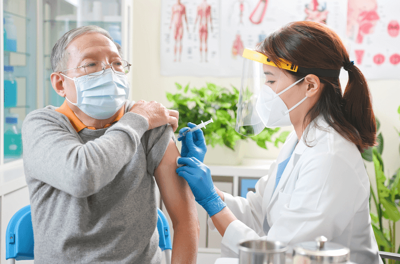 An Asian man visits with his doctor and receives a shot