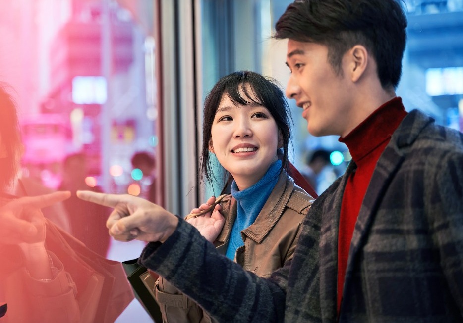 A pair of consumers peer into a shop window