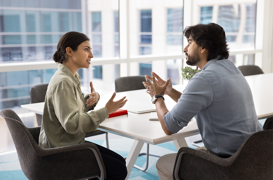 Indian man and woman meeting in an office setting with a red notebook