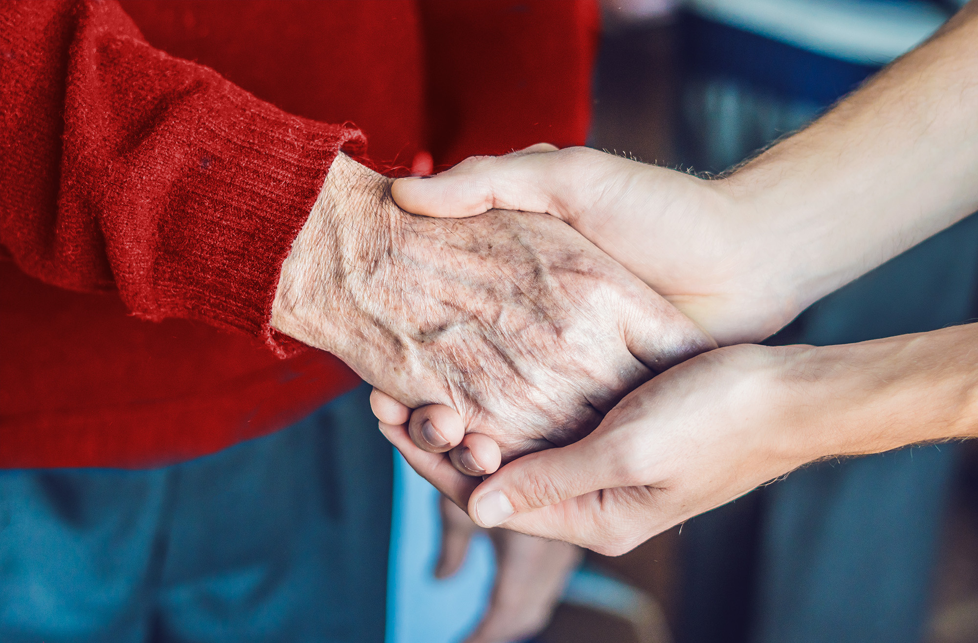 A close up image of a woman holding an elderly person's hand.