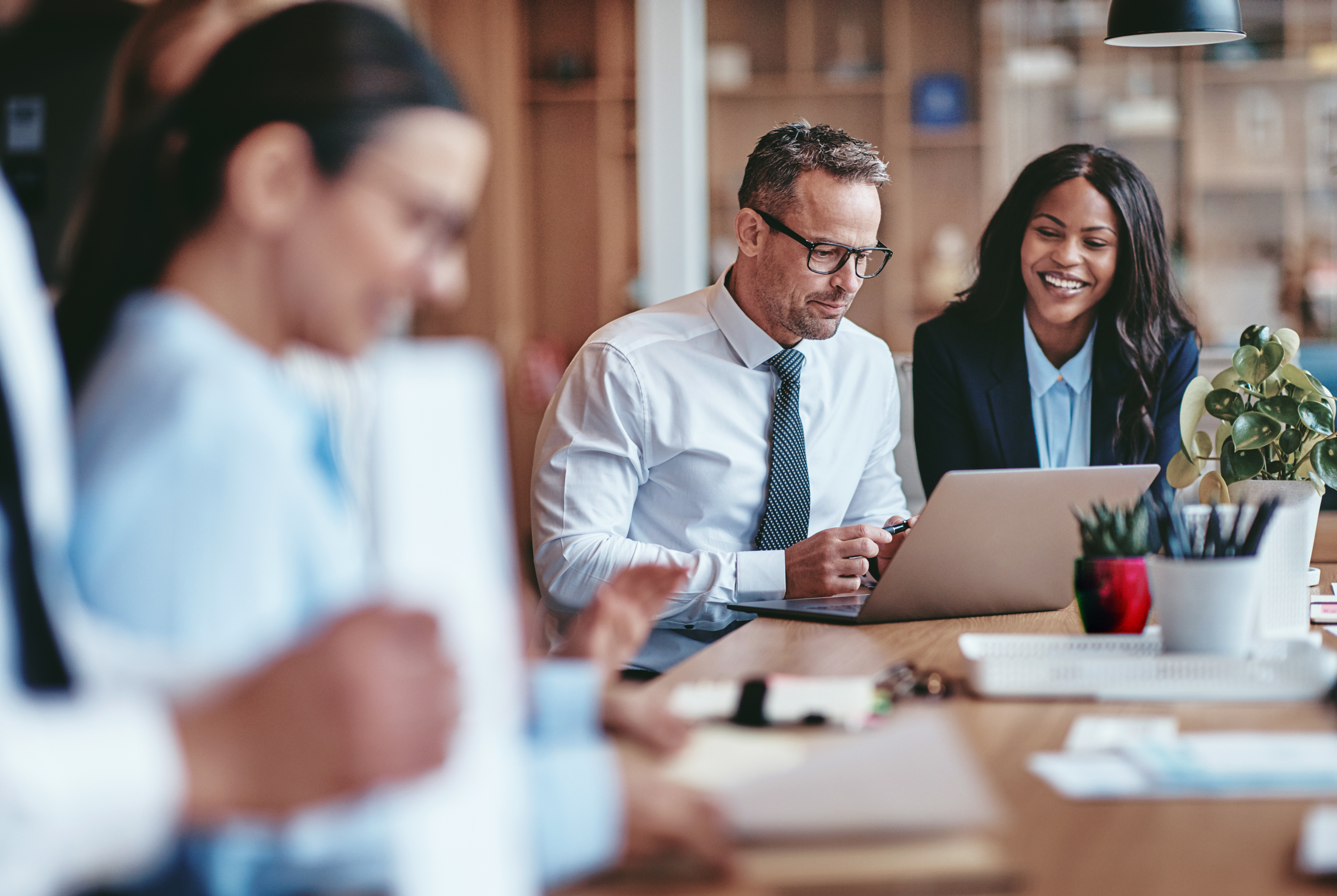 Man and woman looking at a laptop while smiling during a business meeting Man and woman looking at a laptop while smiling during a business meeting