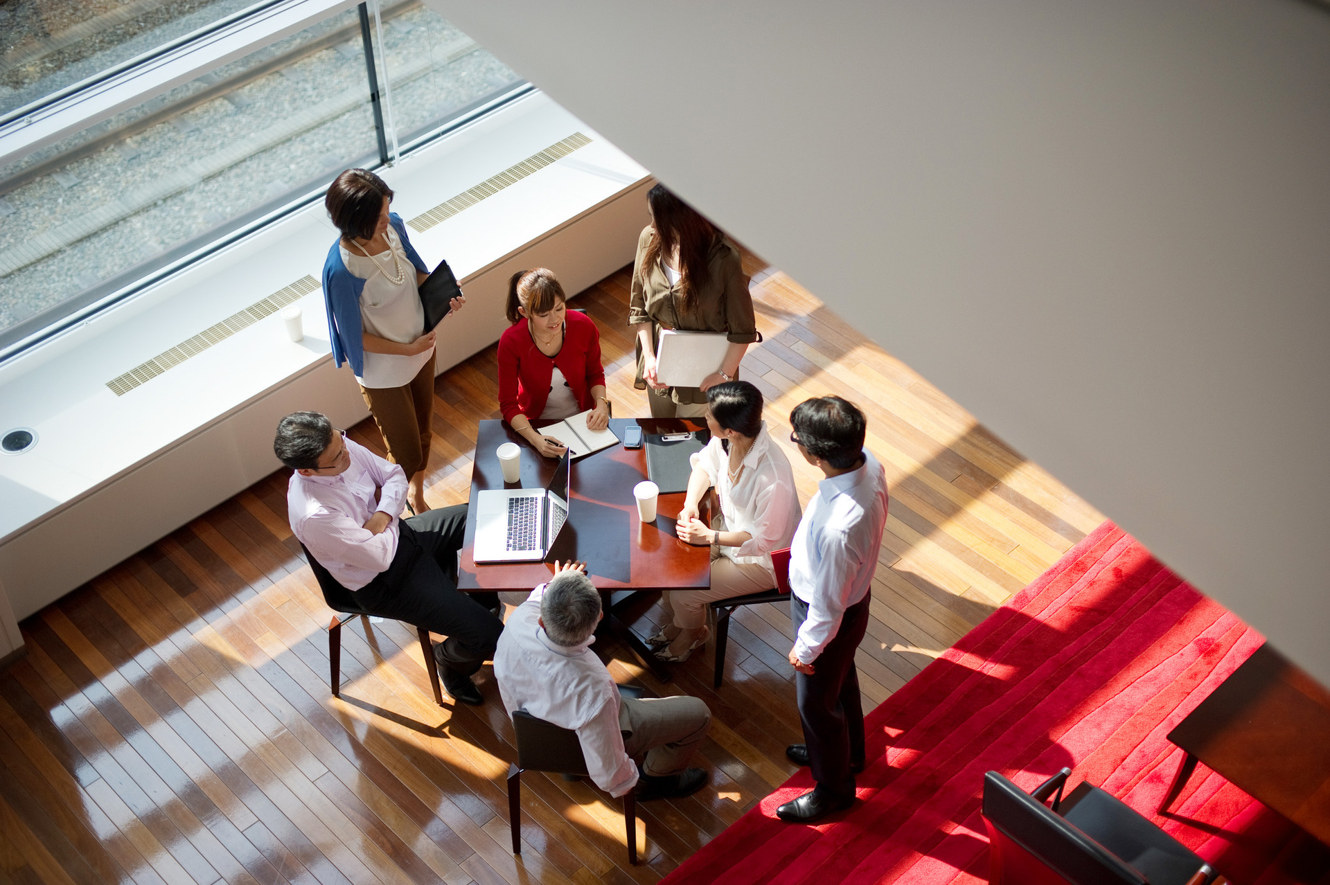 Office Team Meeting at a Round Table with Red Carpet Flooring