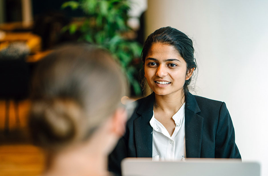 An engaged woman looks up from the Learning Gateway application to discuss a case with a colleague