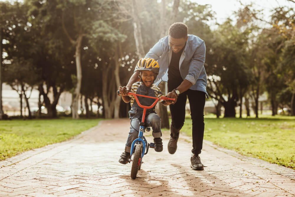 Man teaches young son to ride a bike for the first time