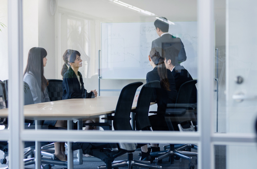 Grouping of Japanese professionals brainstorming in a glass walled office
