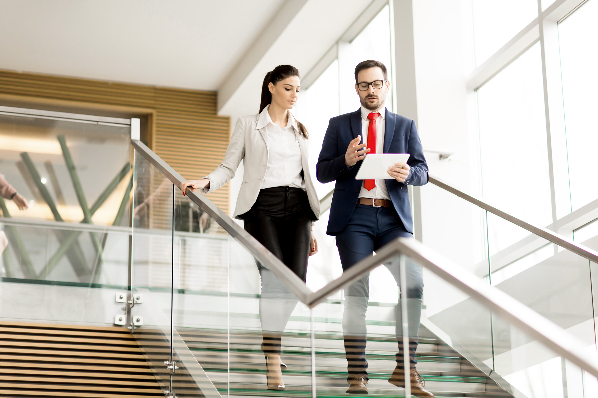 Two businesspeople walking down a set of stairs while conversating