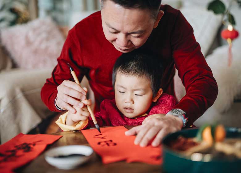 A grandfather assists his grandchild in caligraphy