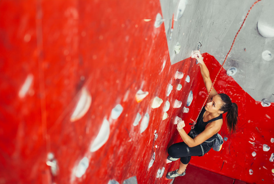 A rope climber rapples up a rock wall with a bold red path