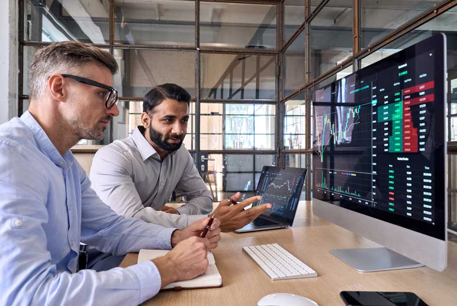 A pair of experts peer at an analytics dashboard on an oversized computer screen
