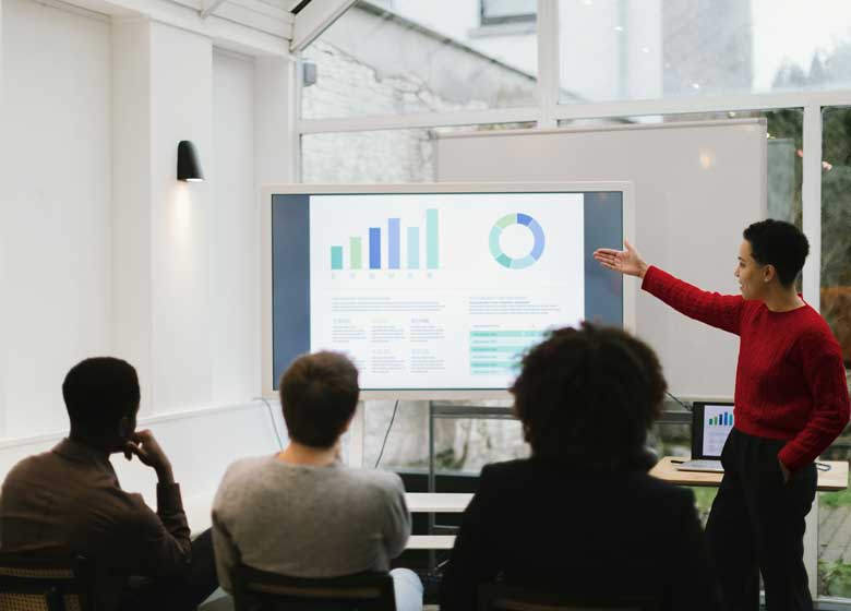 A female teacher stands before a rapt audience, gesturing at numbers