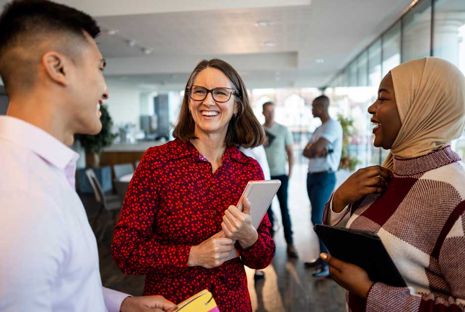 A woman talks excitedly with a circle of colleagues in an office.