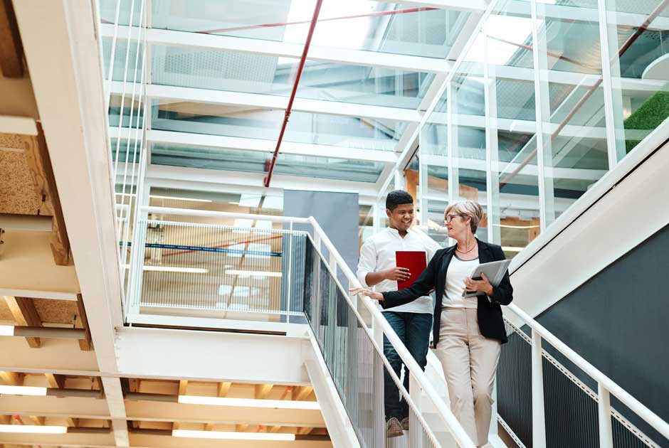 A pair of colleagues descend the stairs, consulting with each other.