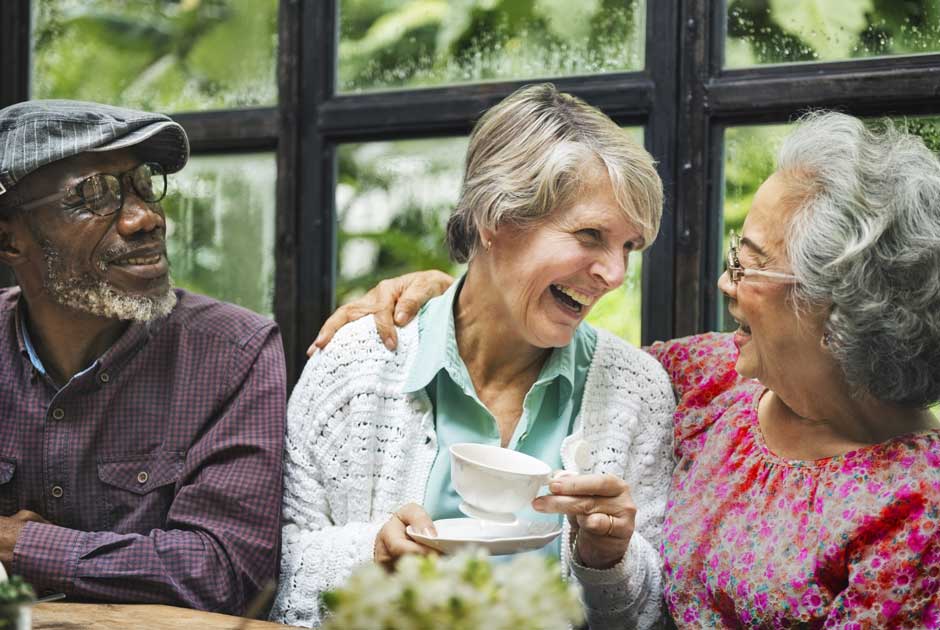 A diverse group of seniors chat over a tea
