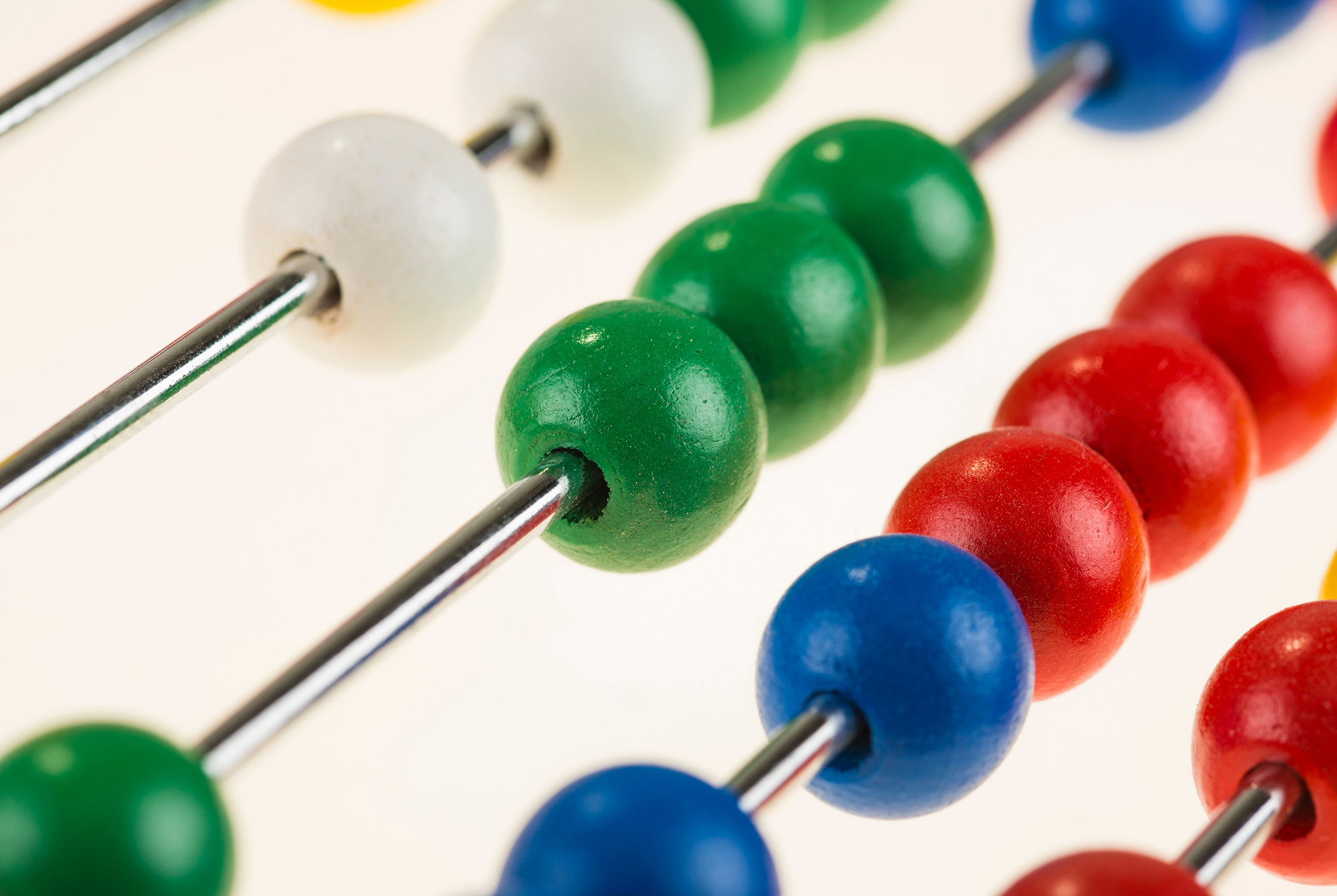 A close view of a colorful abacus, red beads counted across — the precise calculation behind every pension promise.