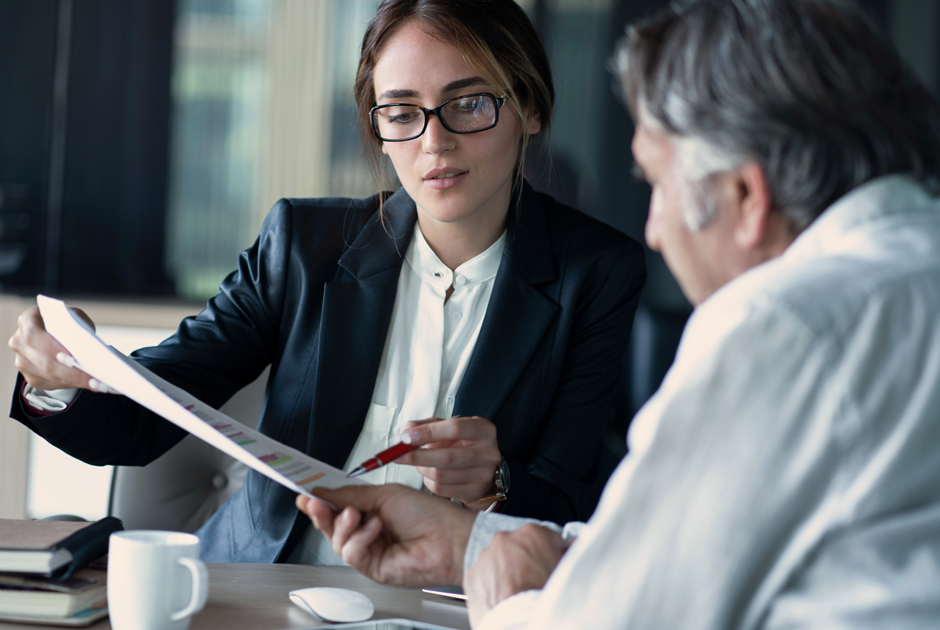 A woman points out an insight in an operational benchmarking report to a client