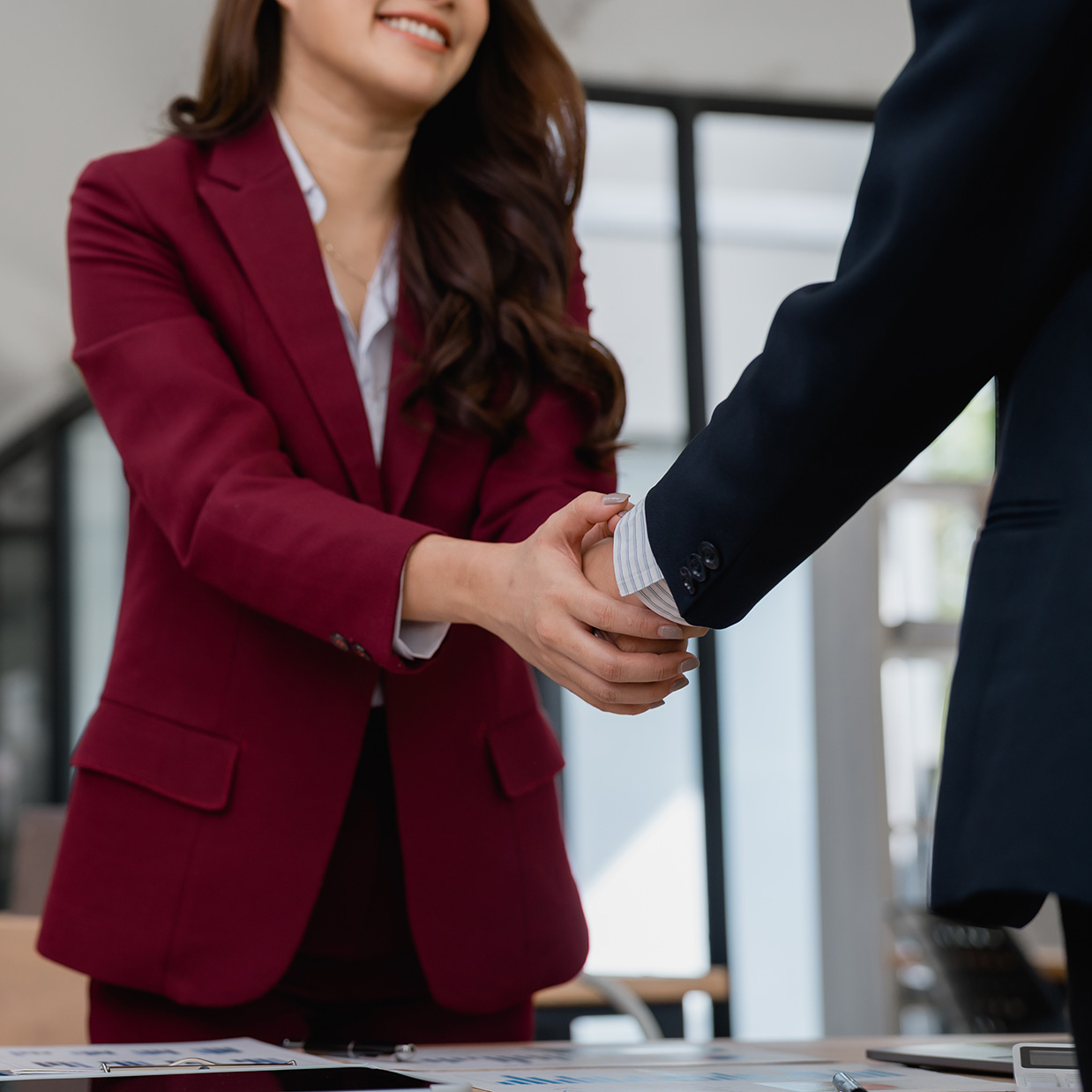 A woman and man shaking hands in a professional setting