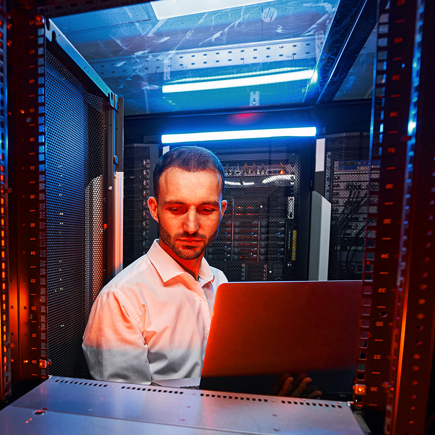 Man in a server room working on a computer