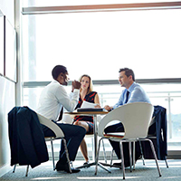 Three people sitting at an office desk taking