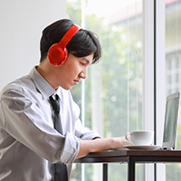 Man wearing red headphones and sitting at a desk with a laptop