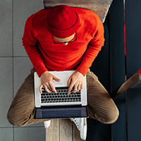 Birdseye view of man in red shirt working on a laptop