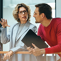 One woman and one man in a red shirt standing and talking