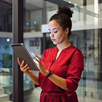 Woman in red dress standing and using a tablet