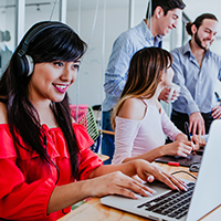 Woman  in red dress working on laptop with three people beside her