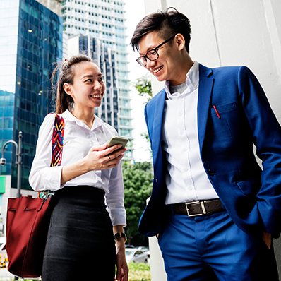 Two business people looking at a report on a phone outside in a city.