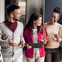 One man and two women standing and talking